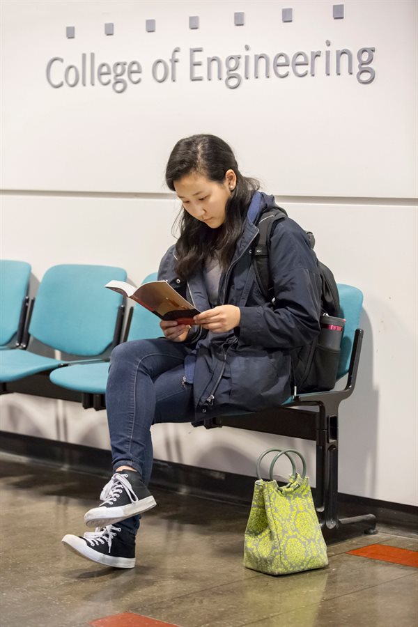 Student reading a book in the hall near ECS offices